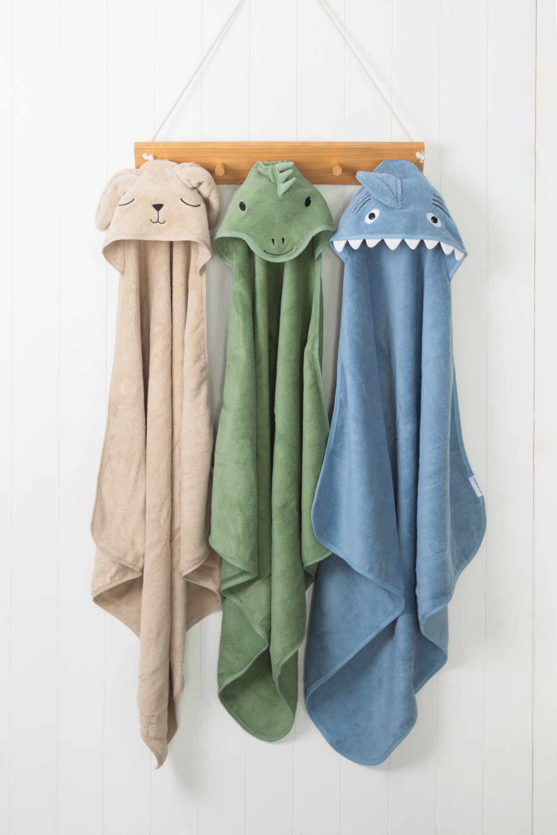 Three character towels (bunny, dino and shark) hanging in a studio setting
