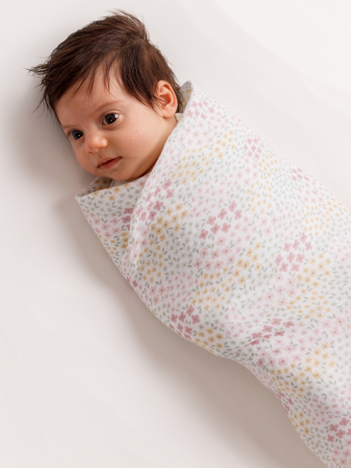 Baby awake and swaddled in a floral cotton fabric