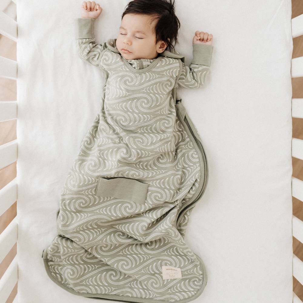 Baby sleeping in a cot with Bo and Ko maori designed Woolbabe sleeping bag
