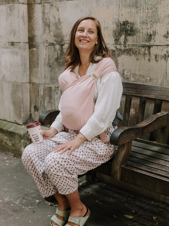 Mum wearing her baby in a pink boba bliss sitting on an outdoor bench