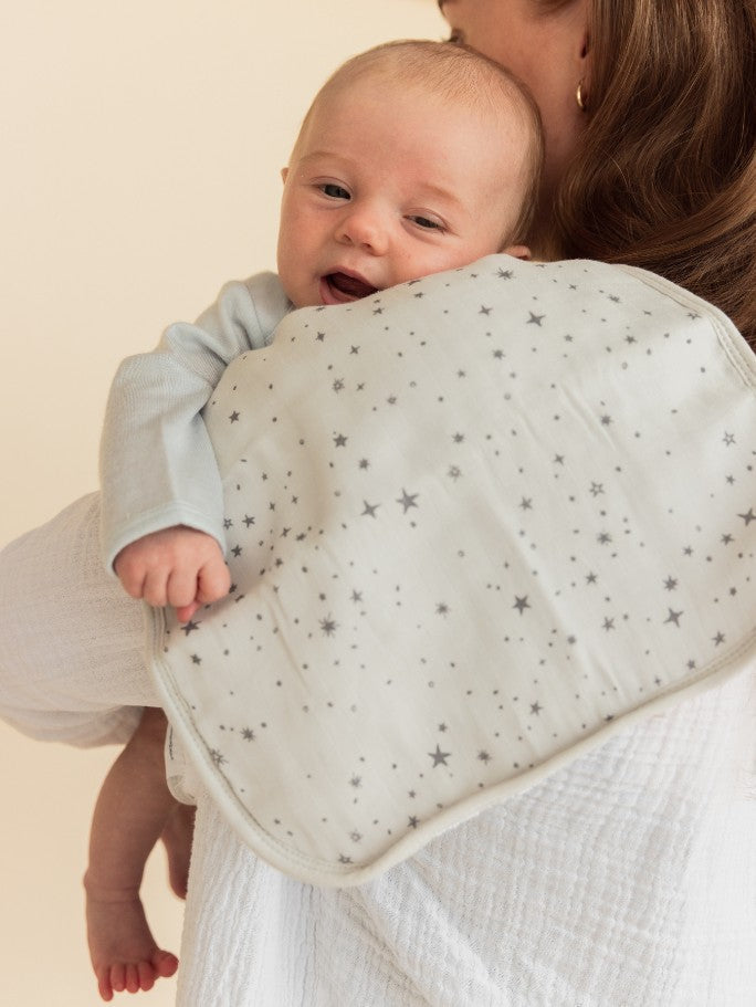 A baby over his mums shoulder with a burp cloth