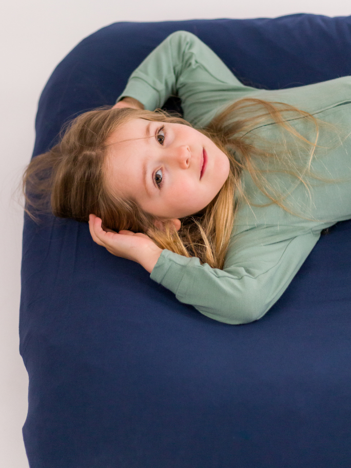 Child wearing fleece onesie lying on inflatable bed