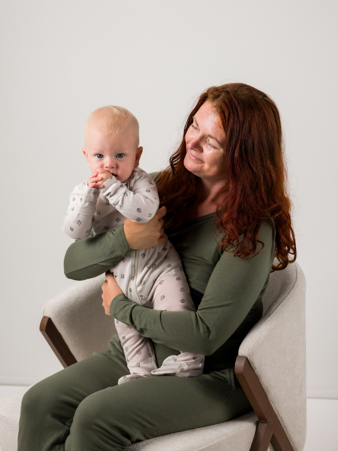 Mum holding baby, both are wearing pyjamas in studio setting