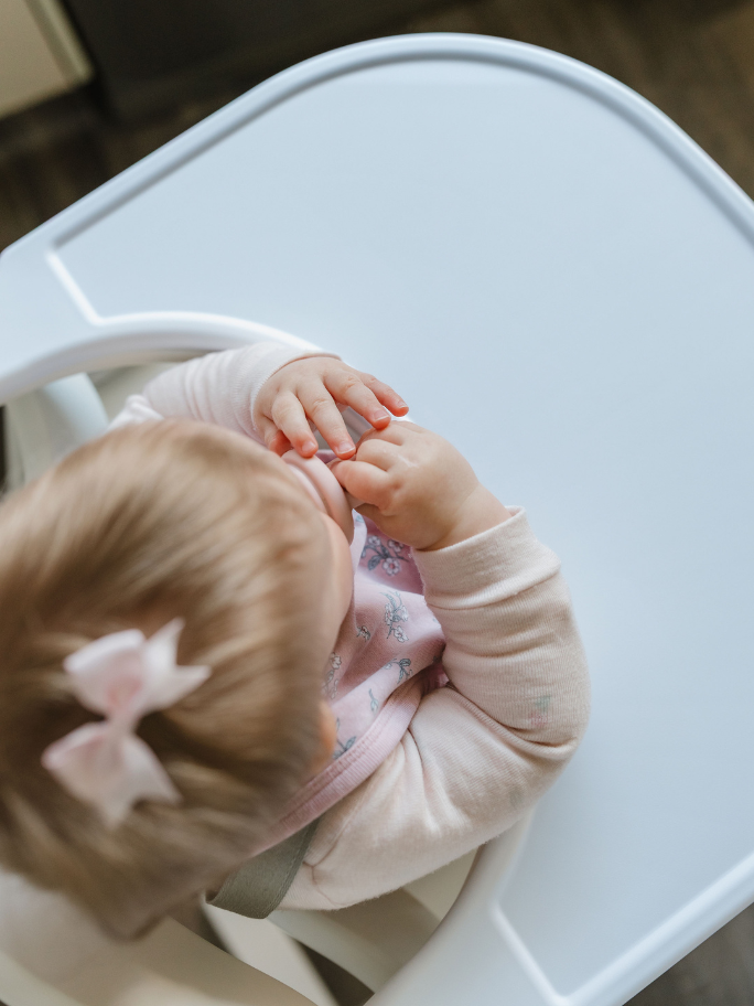 Shot from above of baby in a white highchair with snack