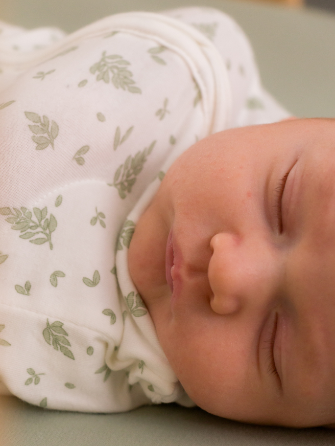 Close up of swaddled newborn in cot