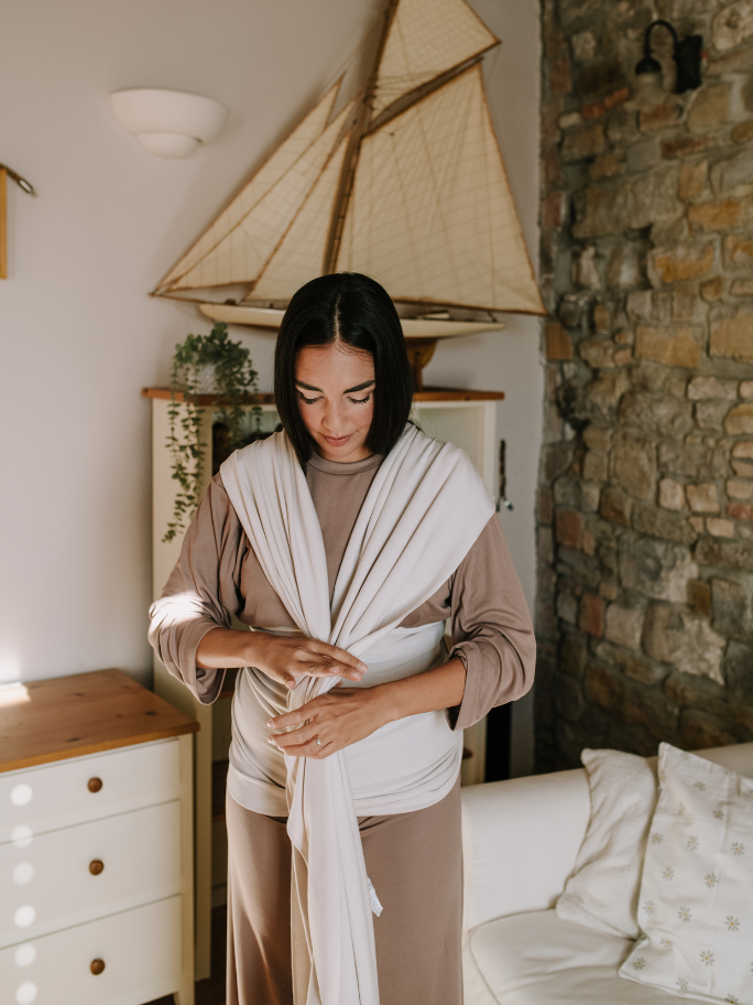 Mum tying a boba wrap in a bedroom setting