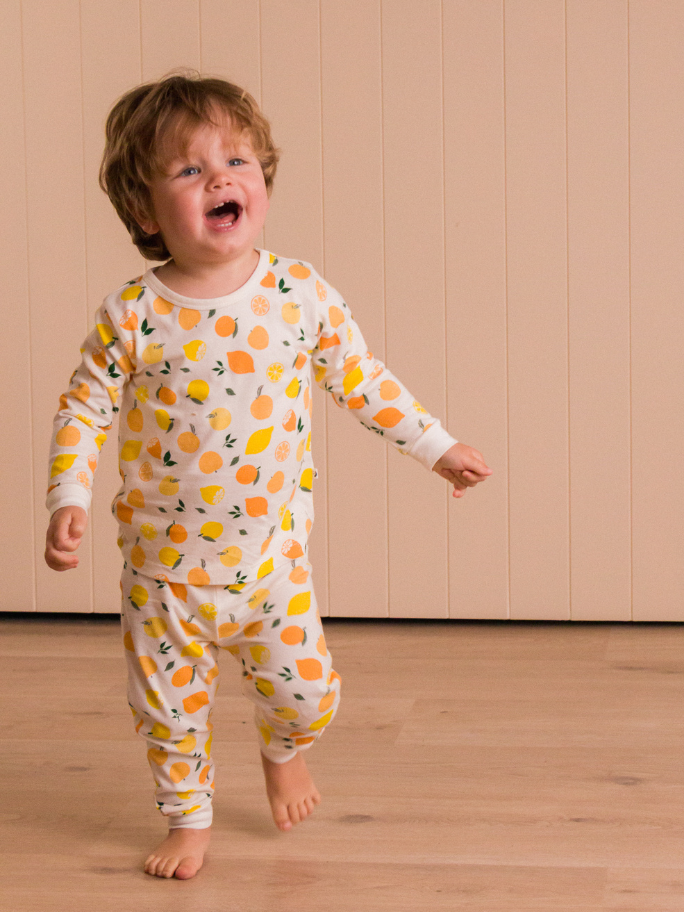 Toddler wearing citrus themed pyjamas running through a bedroom studio setting
