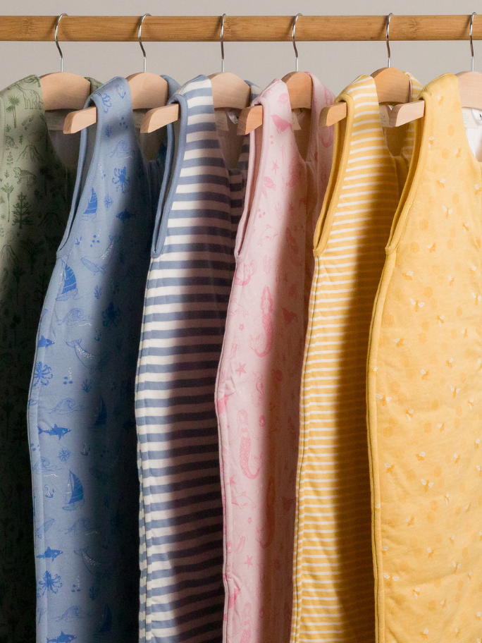 Duvet woolbabe sleeping bag selection in different colours hanging on a rack