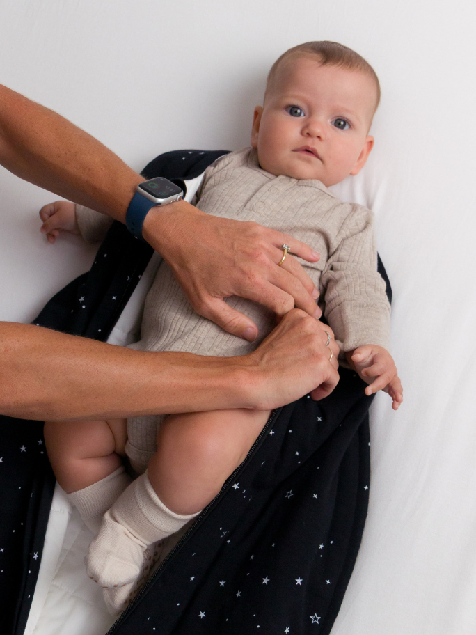 Baby being changed into a duvet sleeping bag with bodysuit and socks underneath