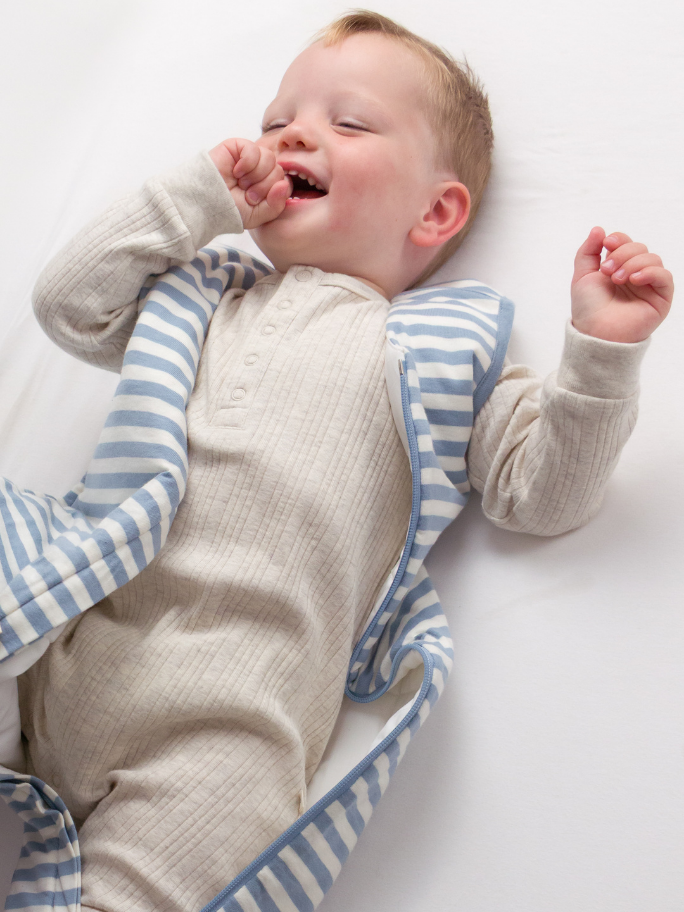 Baby wearing a blue striped sleeping bag with zip open