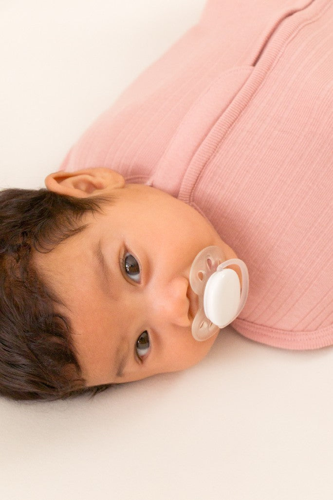 Close up of baby in rib zip swaddle and dummy