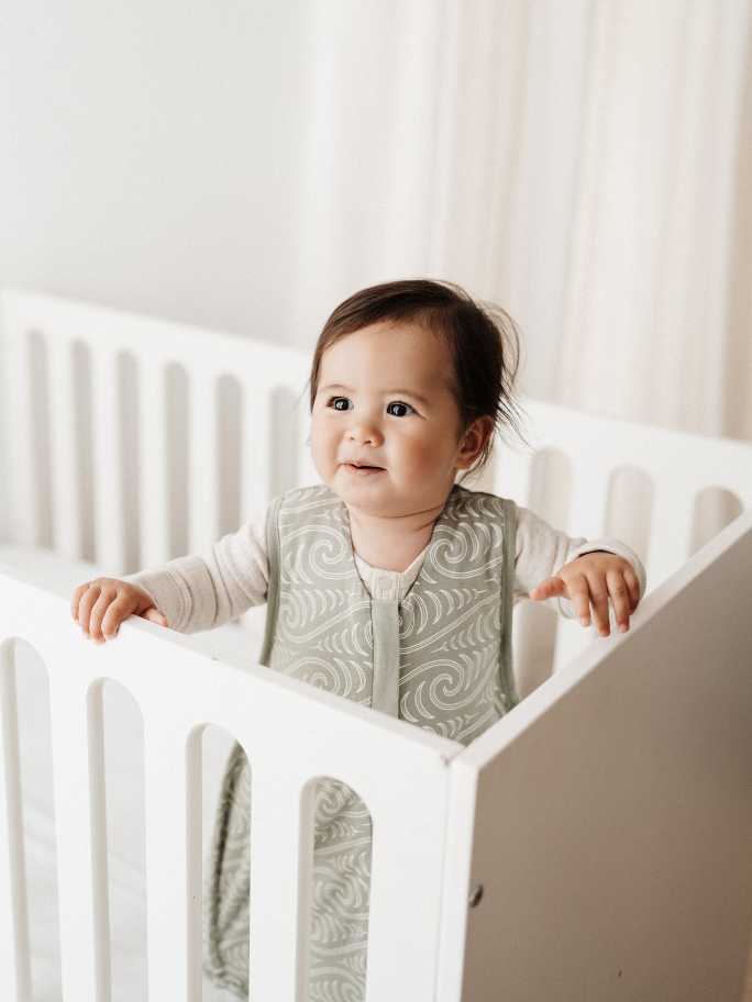 Toddler standing up in cot wearing a Woolbabe sleeping bag