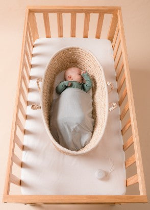 Baby asleep in moses basket which has been placed in the Frank cot