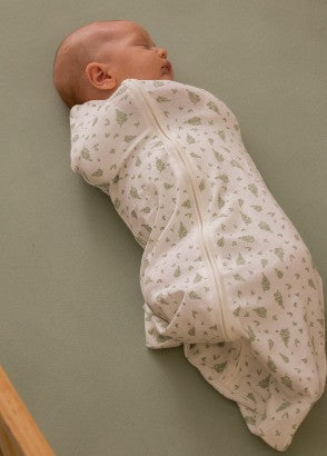 Baby asleep swaddled in the sleep store 0.2 tog organic cotton swaddle bag in little leaves print