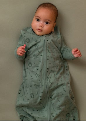 Baby looking at camera wearing the sleep store organic cotton sleeping bag in fern safari