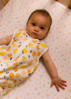 Baby lying awake in cot wearing the sleep store 0.2 tog premium organic cotton sleeping bag