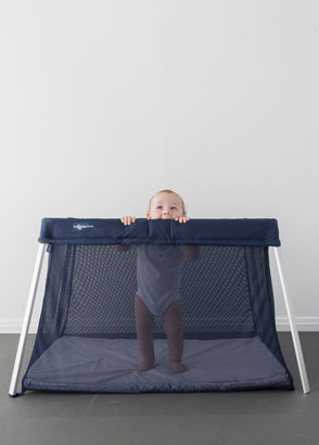 Baby standing up inside a drift travel cot