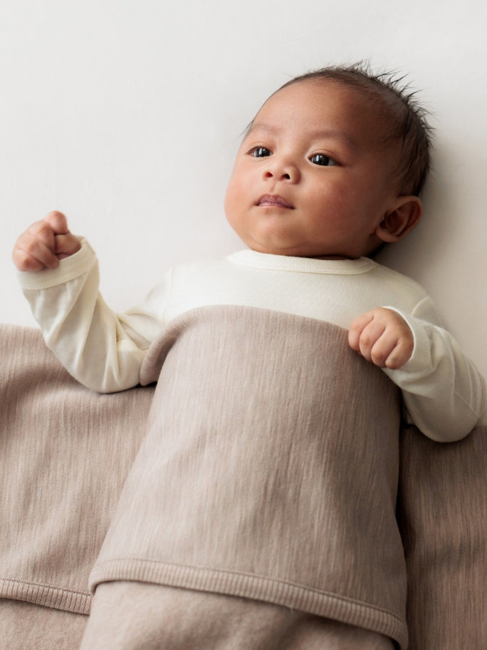 Baby with beige merino blanket over tummy