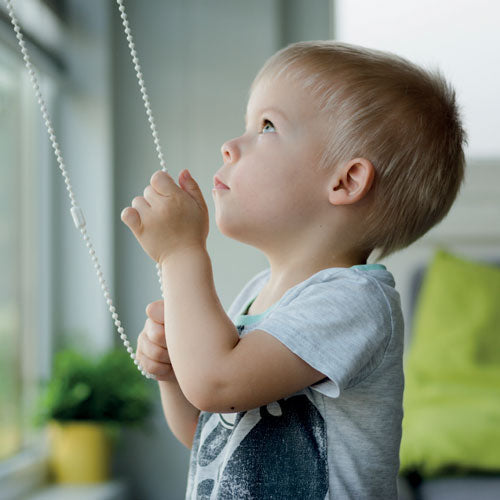 Child using blind pull next to window