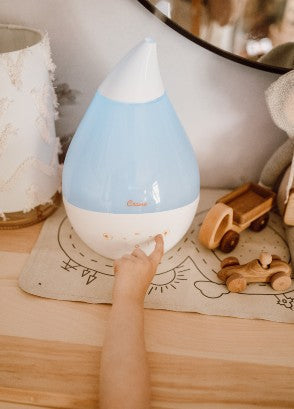 Crane humidifier on a bedside table with a childs hand operating the front button
