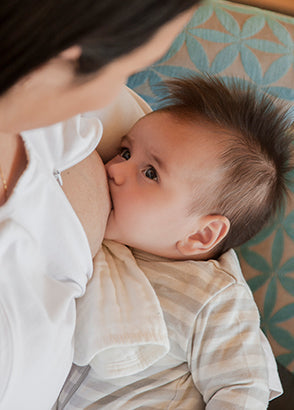 Baby breastfeeding with mum sitting on couch
