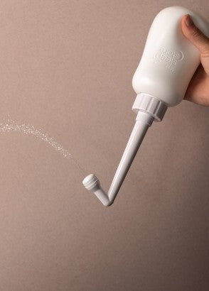 Hand holding peri wash bottle squirting water