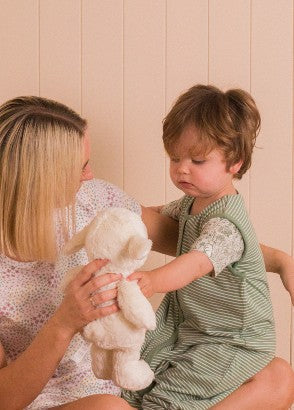 Mother showing lou lou lamb teddy to toddler child in pyjamas