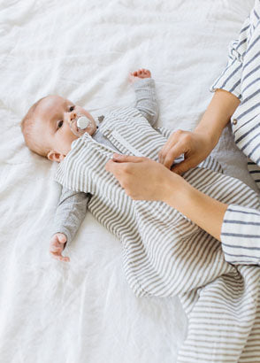 Mother dressing baby in pebble Woolbabe sleepbag