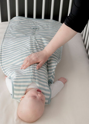 Mum making baby laugh in cot wearing Woolbabe tide sleeping bag
