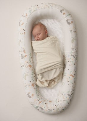 Newborn baby swaddled in miracle blanket fitted swaddle sleeping in Purflo sleep tight baby bed