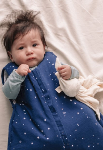 Baby in navy with stars woolbabe sleeping bag in cot