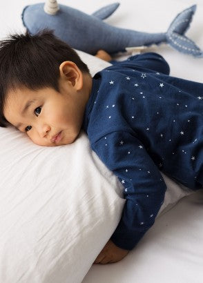 Toddler lying on pillow wearing Woolbabe tekapo stars PJ