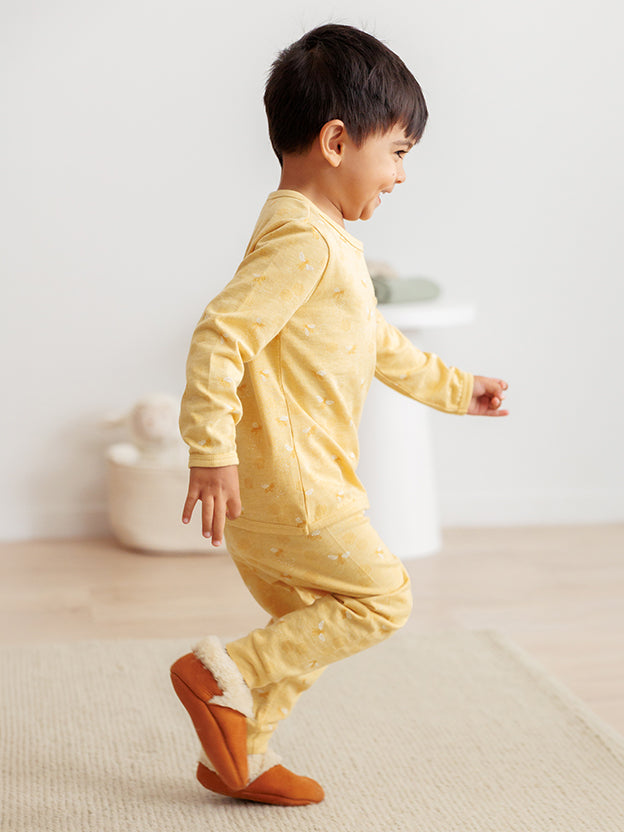 Toddler running wearing yellow pyjamas and brown booties