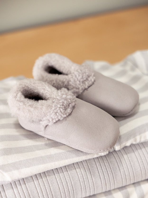 Woolbabe baby booties in grey on top of a striped sleeping bag
