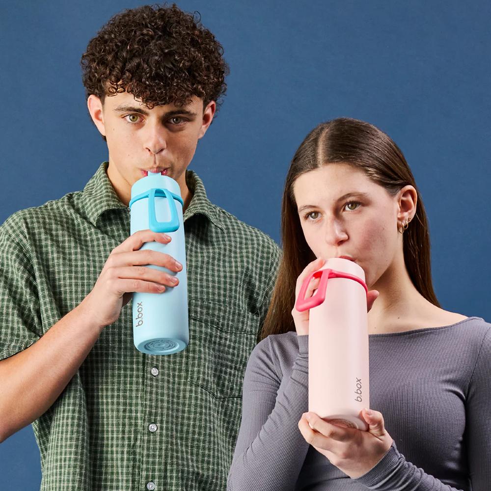 Two people drinking from b.box water bottles against a blue background