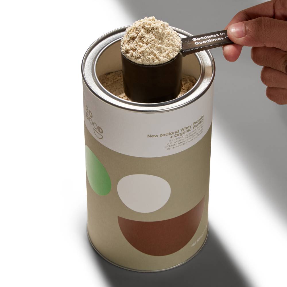 Canister of New Zealand Whey Protein with scoop of protein powder