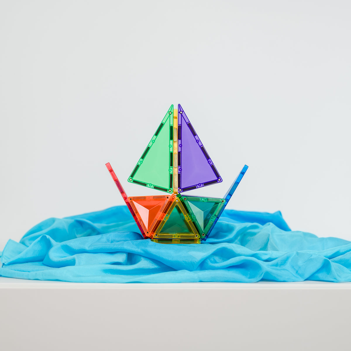 Colorful sailboat made of Connetix  interlocking triangles on a blue fabric background