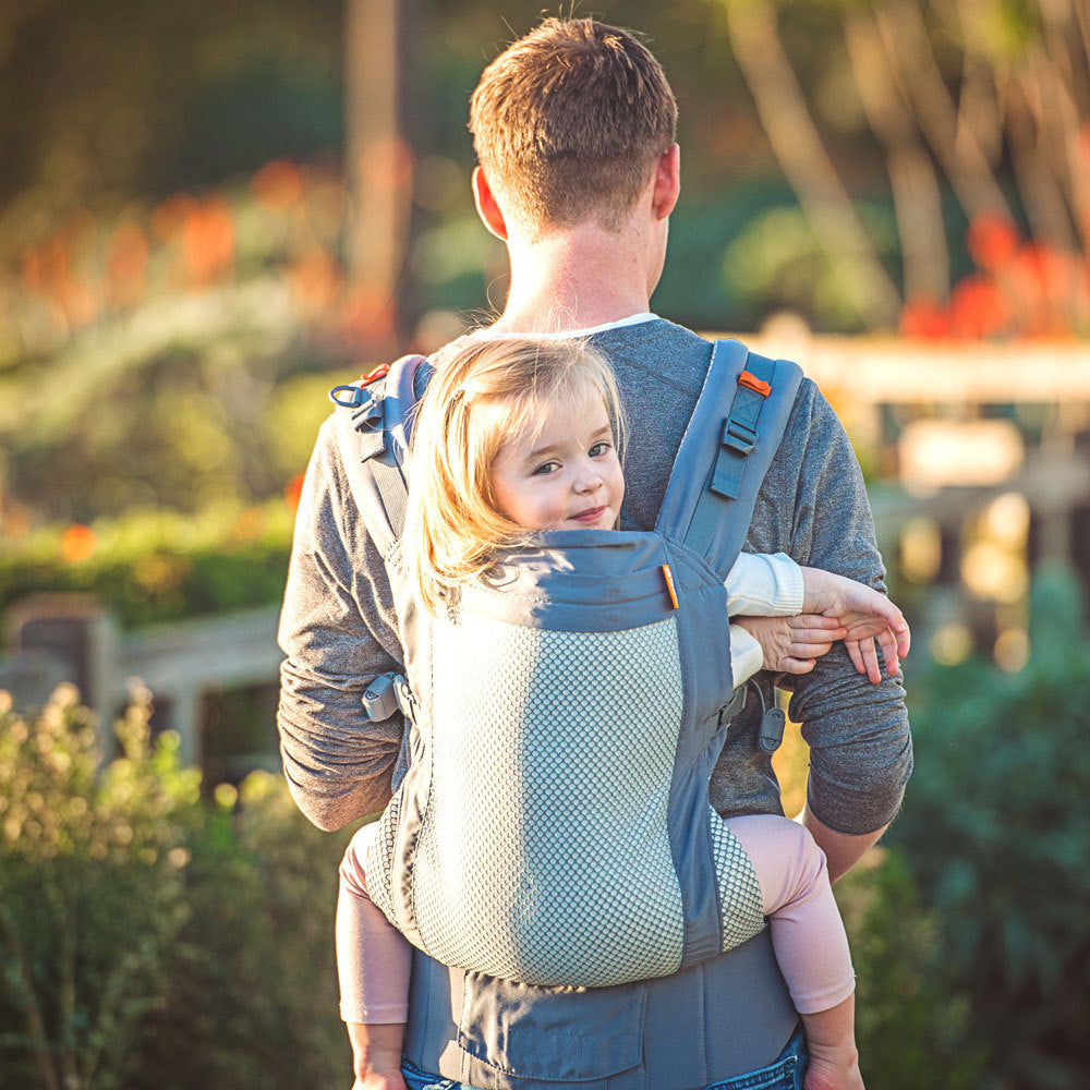 Man carrying a child in a baby carrier outdoors