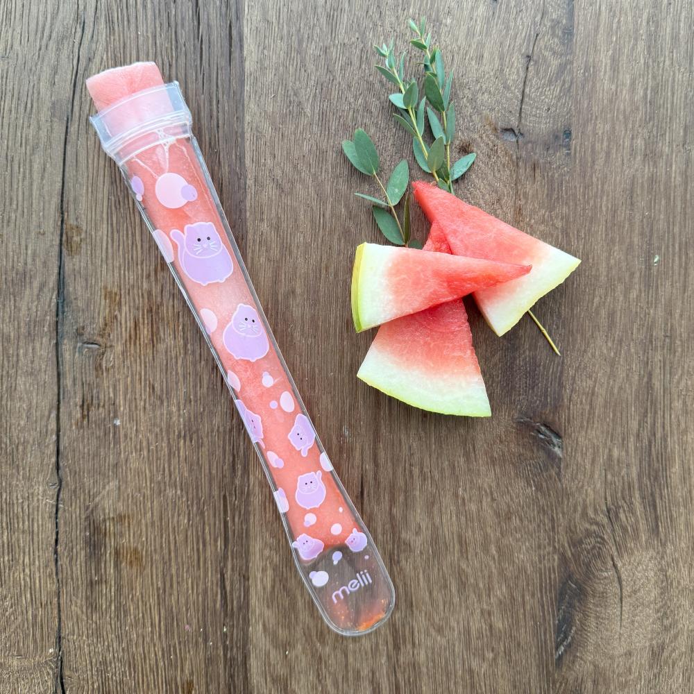 Meili branded ice pop with watermelon slices on a wooden surface
