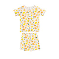A two-piece kids' short-sleeve set featuring a cream-colored t-shirt and shorts with an all-over lemon and orange print, displayed flat against a solid white background.