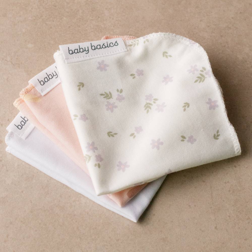 Stack of baby wash cloths with floral pattern on a beige background