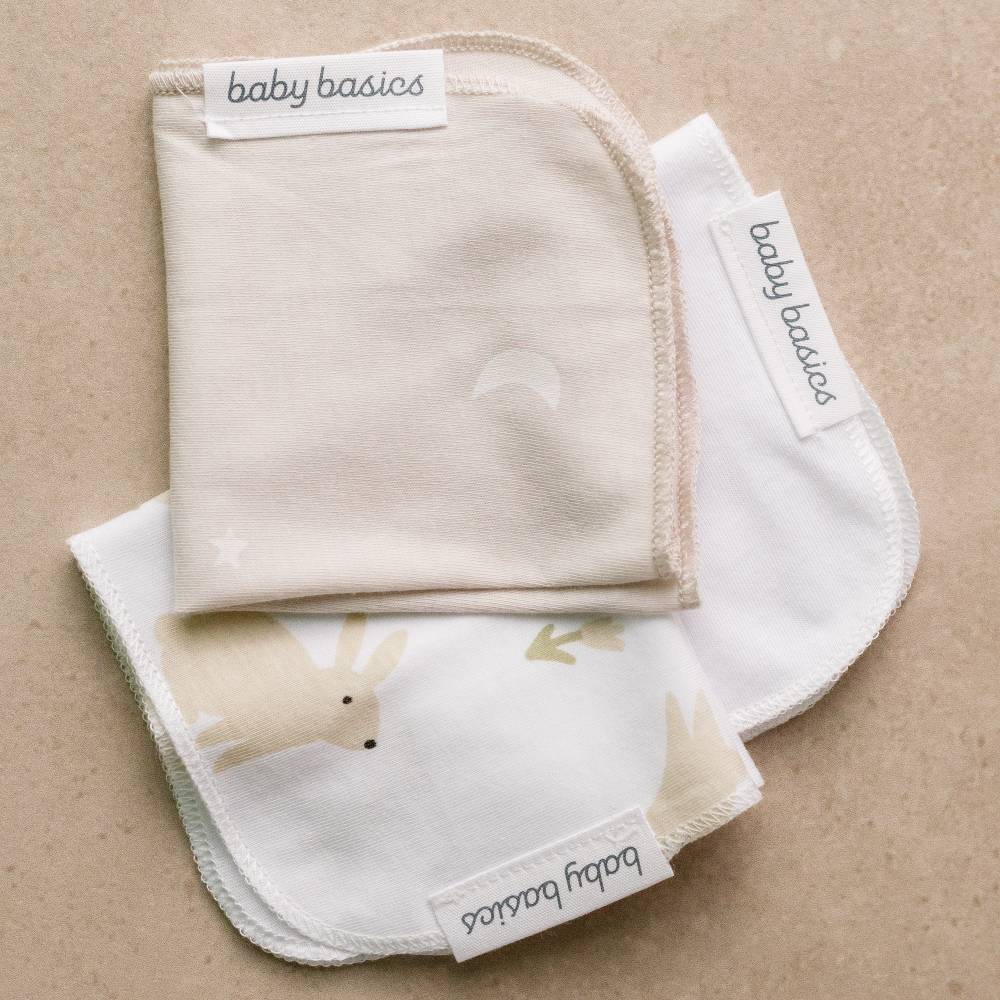 Baby wash cloths with animal print and 'baby basics' label on a beige background