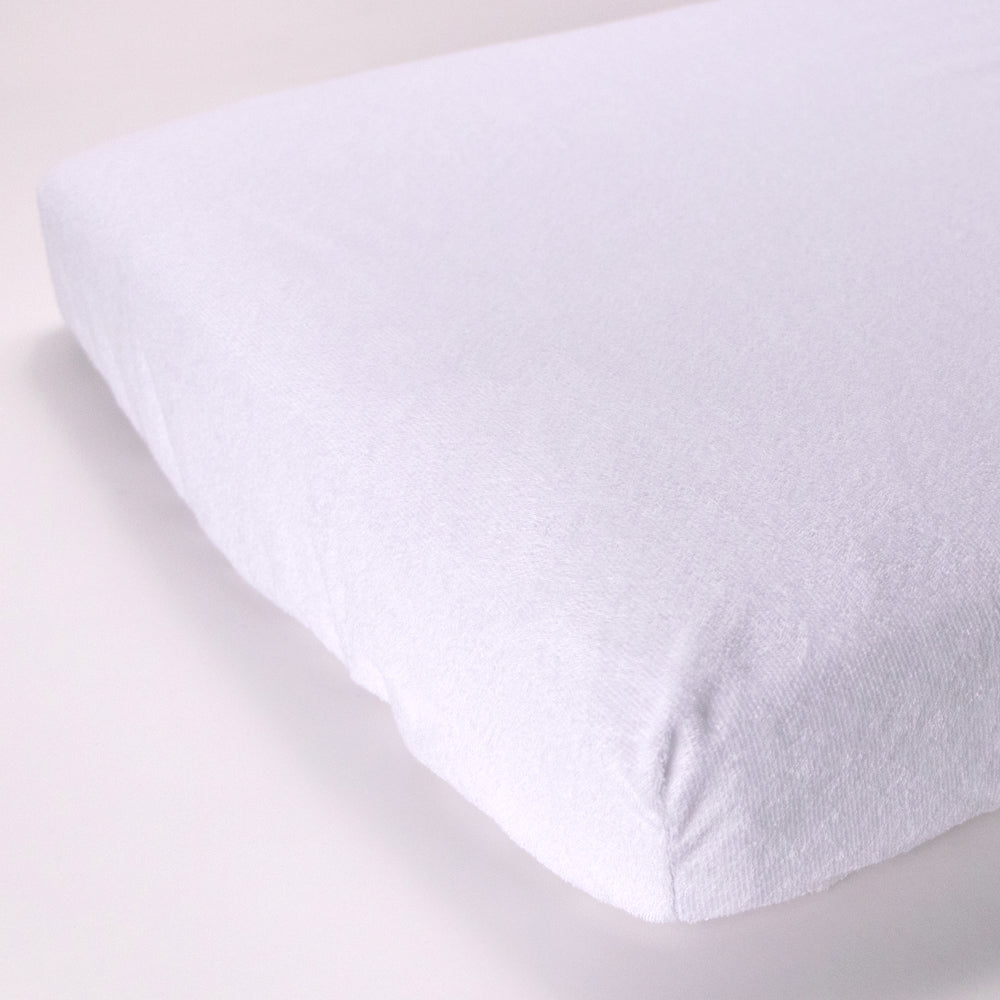 White terry mattress protector on a mattress with a light background