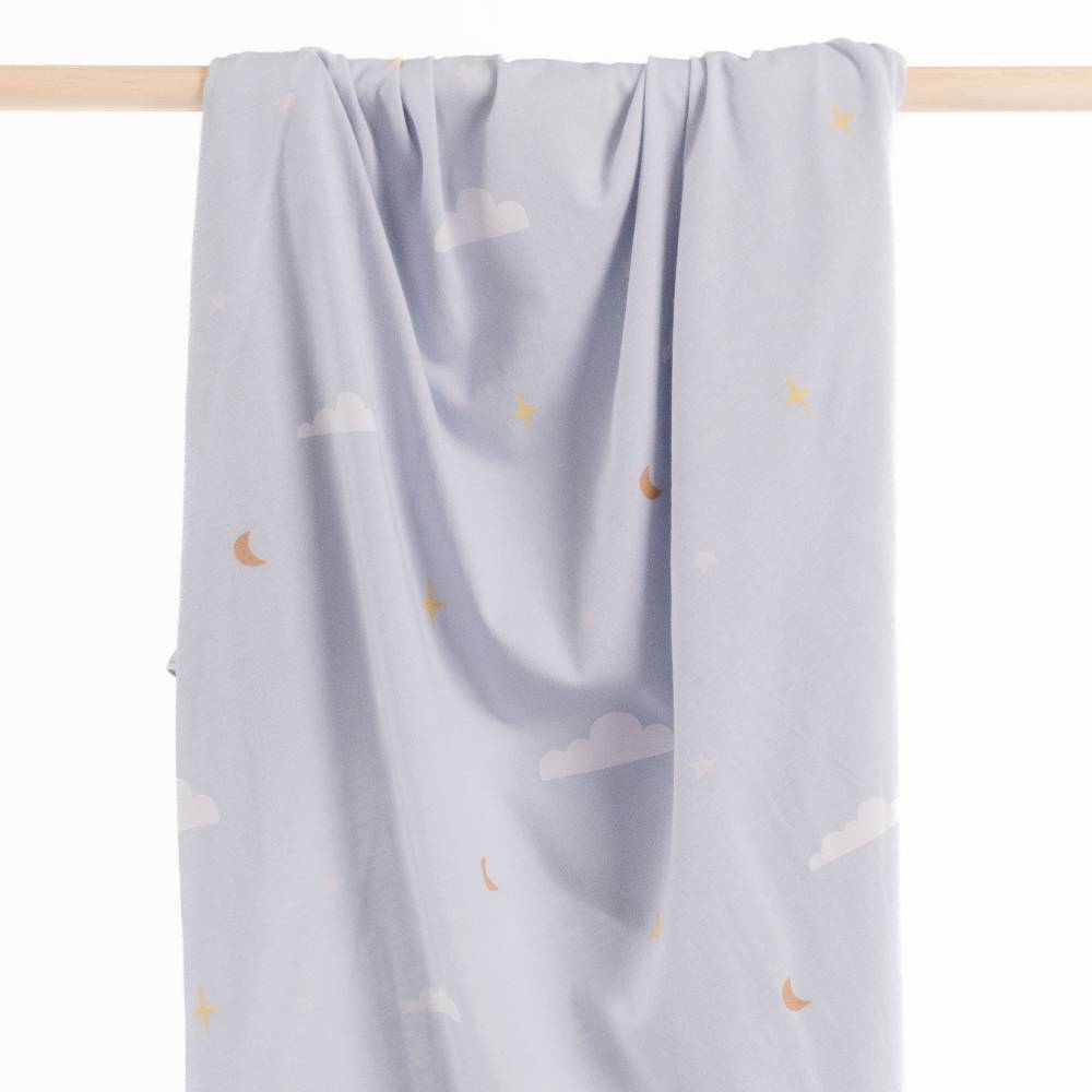 Light blue baby swaddle blanket with cloud and moon patterns hanging on a wooden rod.