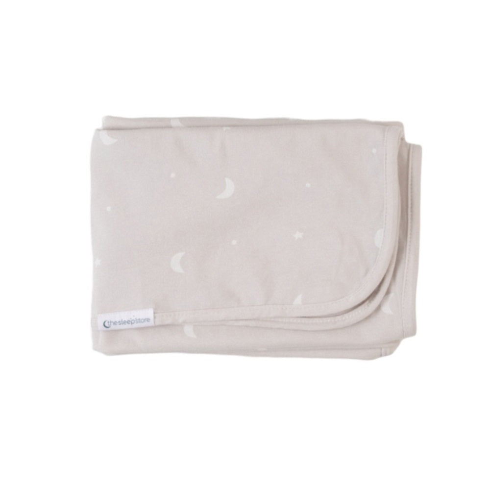 Folded beige blanket with small white moons and stars on a white background