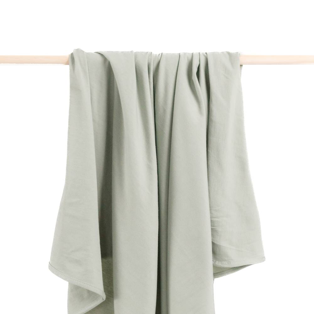 Green Baby Swddle Blanket draped over a wooden rod on a white background