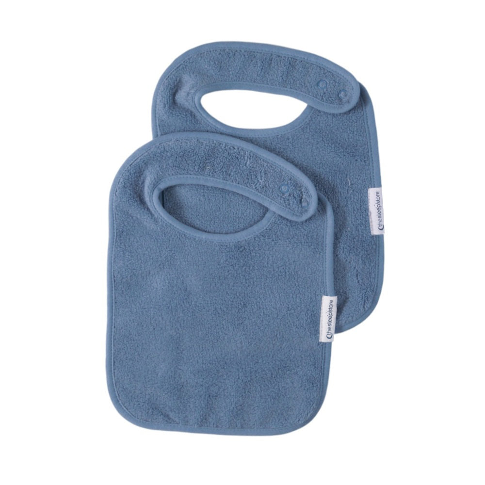 Two blue terry cotton classic style bibs with snap closure on a white background