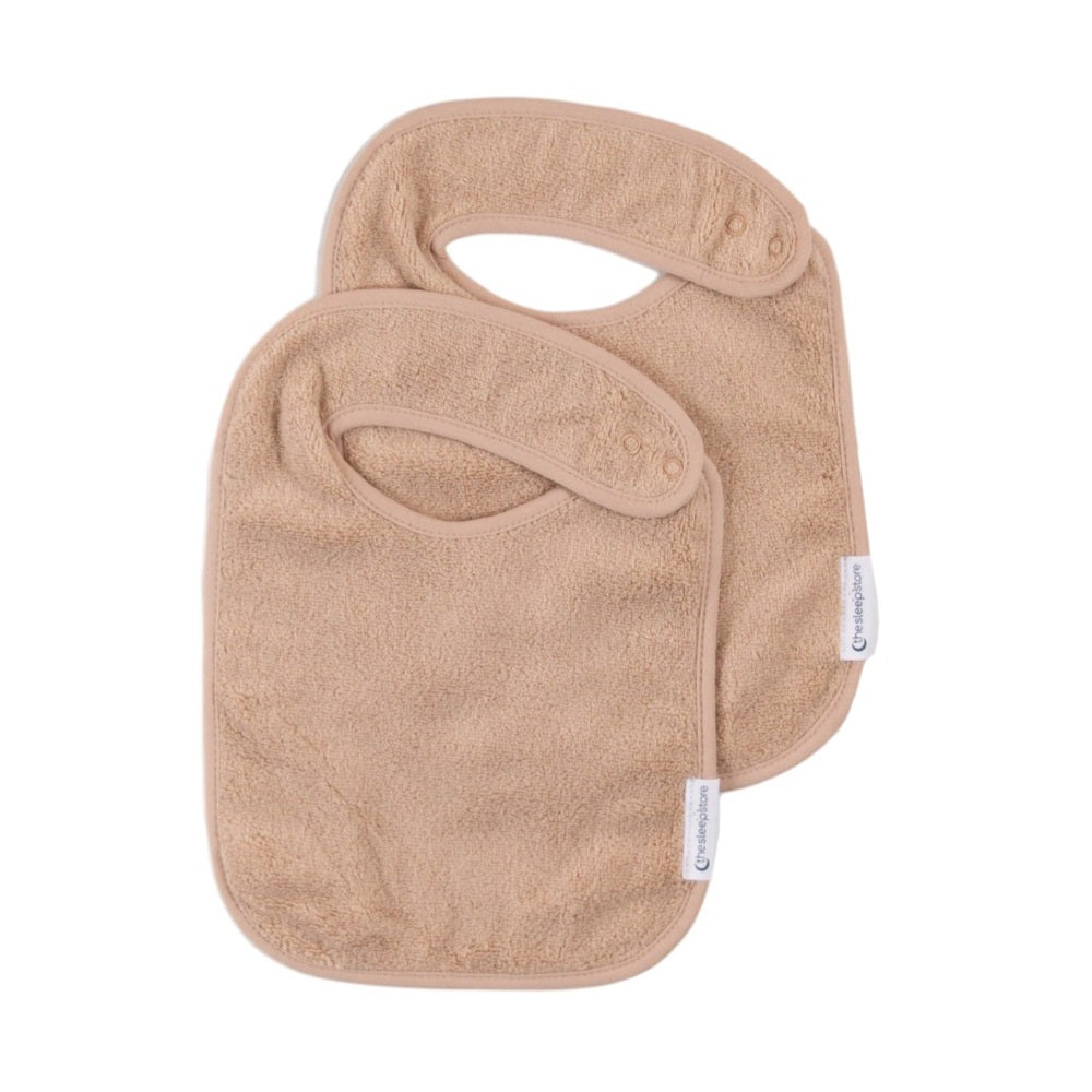 Two oat coloured baby bibs on a white background