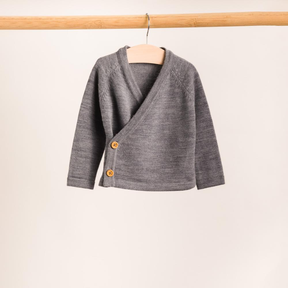 Gray children's merino kimono cardigan on a wooden hanger against a beige background