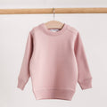 A light pink long-sleeve merino fleece/tencel crewneck sweater hanging on a wooden hanger from a wooden clothes rack, set against a plain off-white background.
